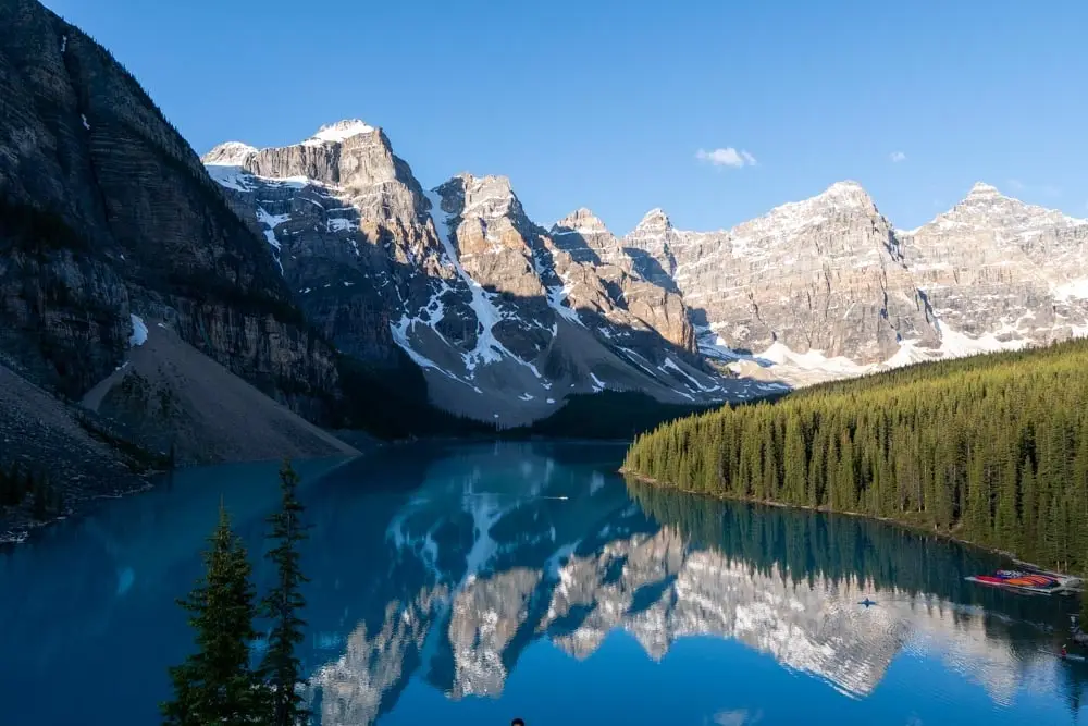 Sunrise light on peaks reflected in calm turquoise water.