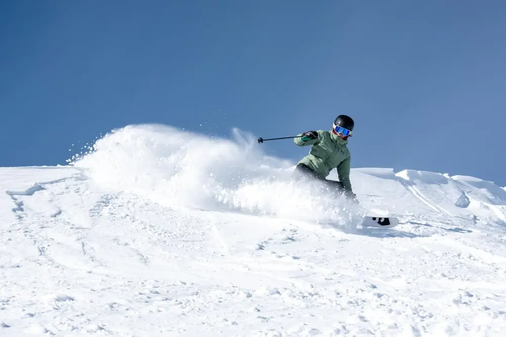 Original skier slashing a powder turn in an upper-mountain bowl.